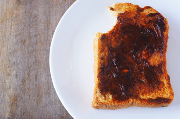 Top view of a bite out of a Vegemite sandwich on a wooden table.