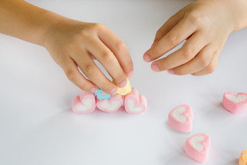 Obraz na płótnie Canvas Child hands play jellys on white table