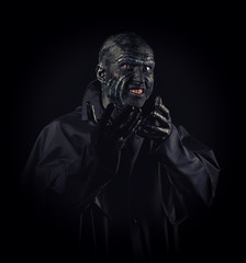 Studio portrait of a man in monster makeup, dark background