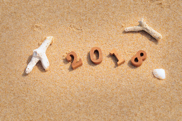 Wood number 2018 on beach background, happy new year concept.
