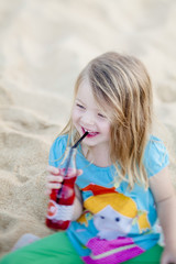 Glückliches Mädchen am Strand trinkt Saft