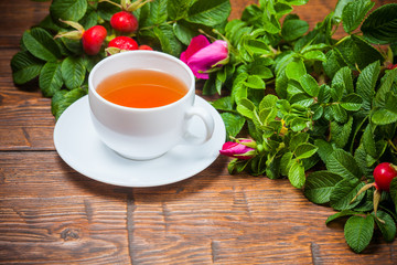 Healthy tea with a dogrose on wooden table