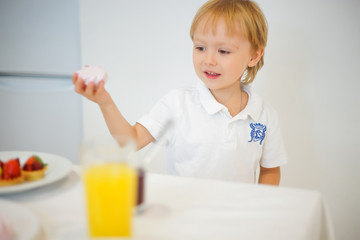 Obraz na płótnie Canvas boy preparing breakfast in white kitchen