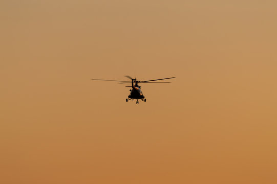 Silhouette of helicopter with sunset sky