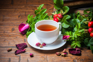 Healthy tea with a dogrose on wooden table