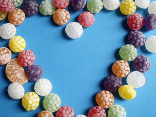Candies forming a heart on blue background