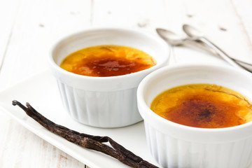 Traditional French creme brulee dessert with caramelized sugar on top, on wooden table

