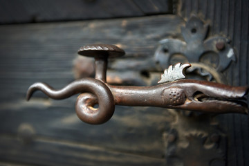 Ornamental vintage iron door handle on wooden door