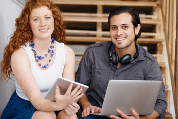 Portrait of two young people sitting at the stairs in office