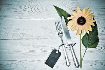 Besteck und Sonnenblume auf einem alten Tisch