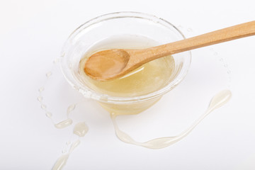 Bee honey in a glass bowl and wooden spoon on  white background