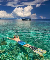 Deurstickers man snorkeling in clear tropical waters over coral reefs © soft_light
