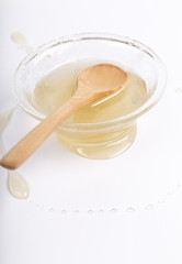 Bee honey in a glass bowl and wooden spoon on  white background
