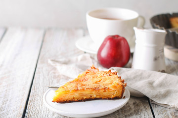 Slice of homemade apple pie on a wooden background. Autumn breakfast with fruit pie and tea.