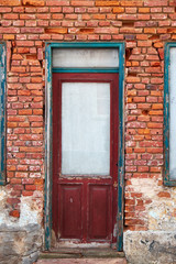 Decayed and weathered door and windows in a ruined facade of red broken tiles, in a townhouse in Elsinore, Denmark