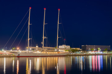 Fototapeta na wymiar Colors of Tarragona port at night with beautiful moored yacht, Spain