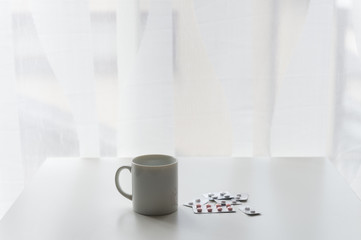 white pills lying next to a glass of water on a wooden table