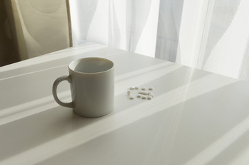 white pills lying next to a glass of water on a wooden table