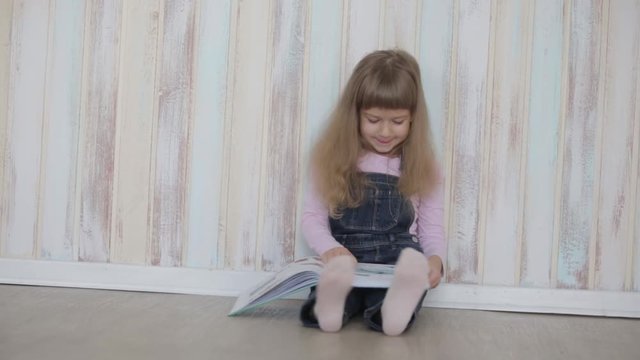 little girl reading a book sitting on floor