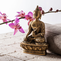 Bronze Buddha over towel and flowers for concept of spirituality