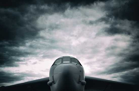 Bomber - big military aircraft front the frontal side. Dramatic cloudy sky above plane
