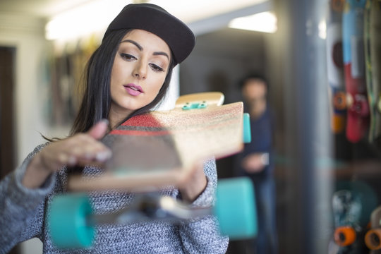 Young woman examining skateboard in shop