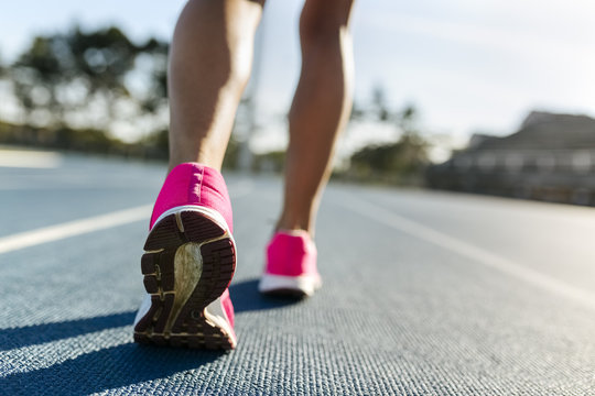 Legs of female athlete running on racetrack