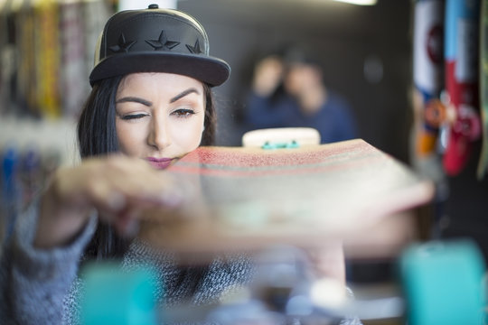Young woman examining skateboard in shop