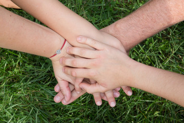 Family hands top each other with grass background