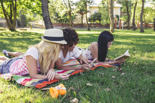 Friends in park reading book and using cell phone