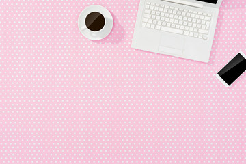 Pink office desktop with white laptop, smart phone and coffee cup. Top view