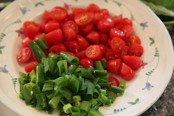 green onions and split cherry tomatoes on a plate