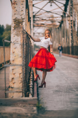 A gorgeous model woman posing on metal rusty bridge. Wind in her hair and red skirt. Awesome...