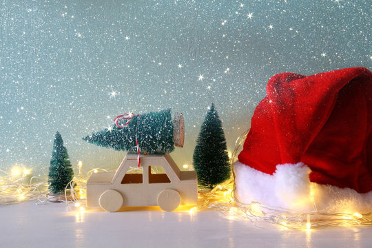 Wooden car carrying a christmas tree next santa claus hat