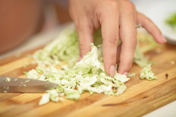 pregnant woman cuts cabbage on wooden Board, close-up