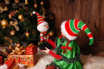 Little girl in suit of the Christmas Elf with gifts