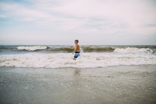Boy standing in sea and enjoying wave at the beach