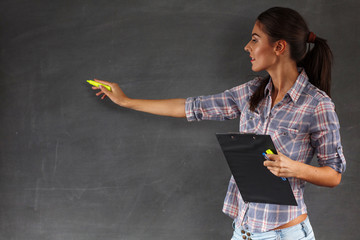 Young pretty female teacher writing on the chalkboard,copy space