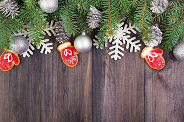 Christmas wooden background with fir branches, decoration balls, snowflakes, stars and cookies mittens. Top view with copyspace.