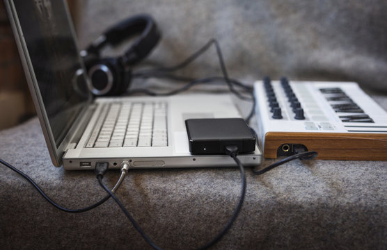 Close-up of laptop computer with musical keyboard on sofa at home