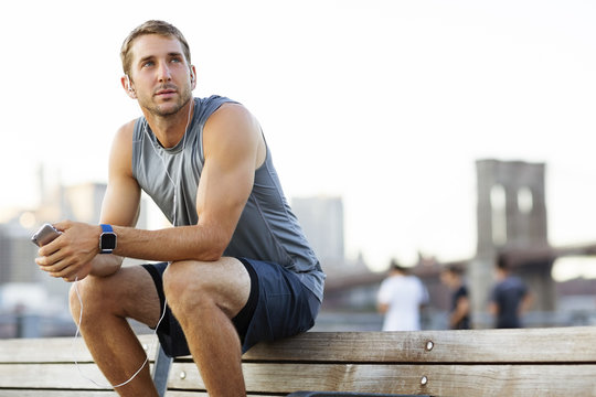 Athlete listening to music while sitting on bench