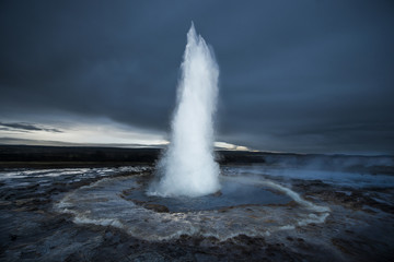 Strokkur geyser erupting against cloudscape