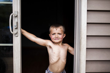 Portrait of shirtless boy standing at doorway