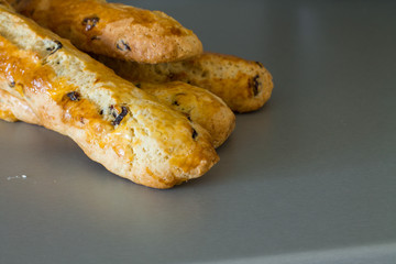 Four freshly baked baguette of biscotti with cranberry before cutting on grey table.