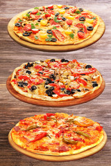 Set of delicious pizzas on wooden background.