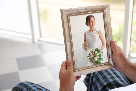 Male hands holding photo frame with picture of young woman. Happy memories concept.