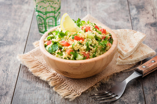 Tabbouleh salad with couscous in wooden bowl on rustic table

