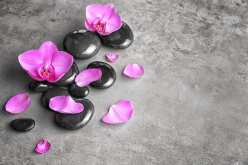 Obraz na płótnie Canvas Spa stones with orchid flowers on grey background