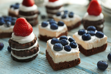 Delicious strawberry and blueberry cakes on wooden table
