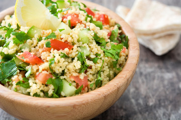Tabbouleh salad with couscous in wooden bowl on rustic table

